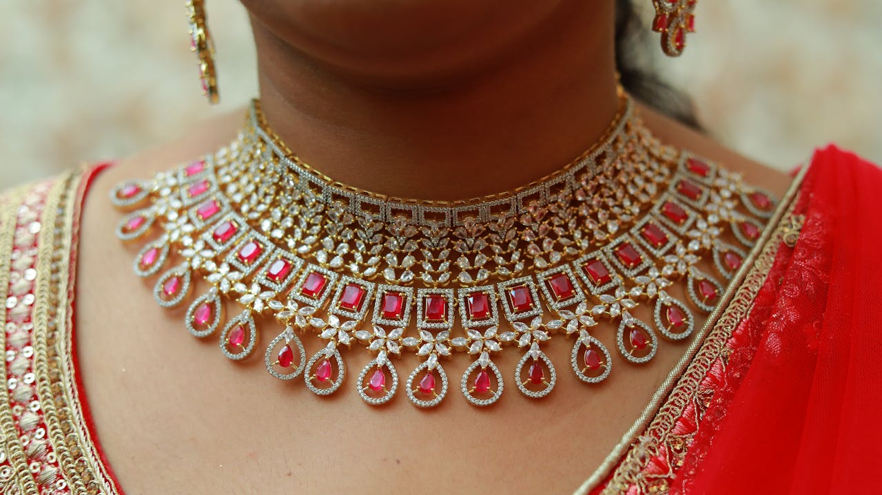 Close-up of an ornate gold and ruby necklace worn by a woman in traditional attire.