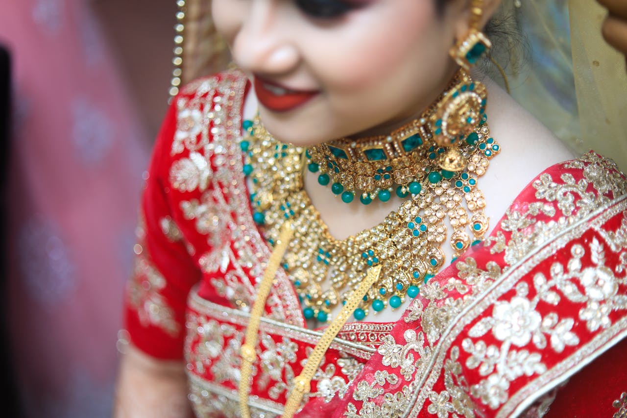 Close-up of an Indian bride in Bhubaneswar wearing ornate jewelry and a traditional red saree.